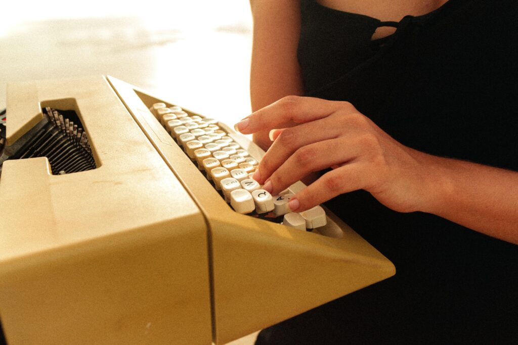 Close-up of hands typing on a vintage typewriter, with a warm, nostalgic feel.